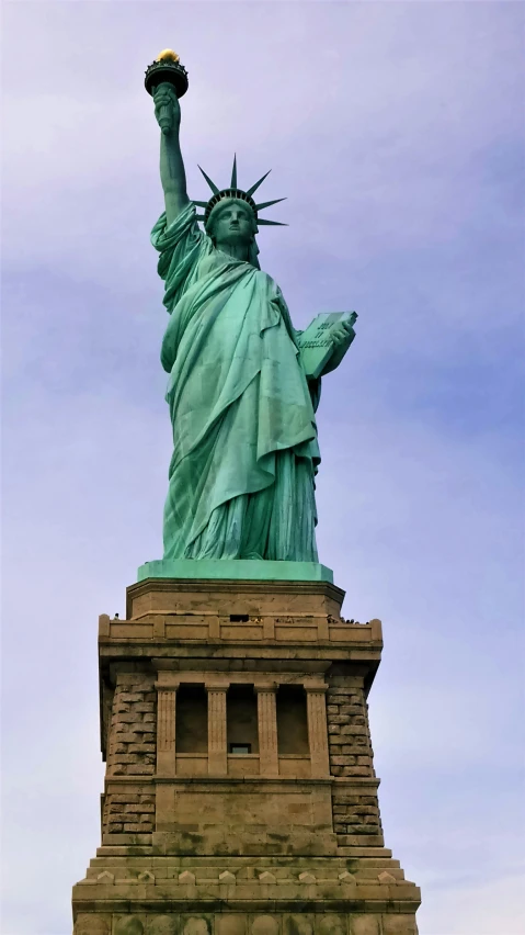 the statue of liberty is against a cloudy blue sky