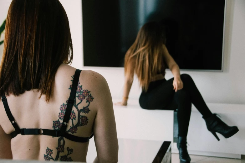 woman with back tattoo sitting on a couch