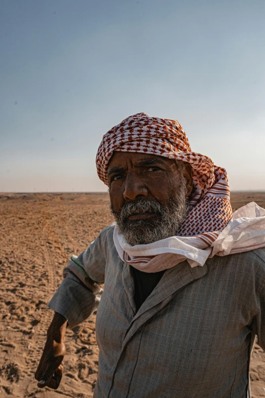 a man stands in the desert while wearing a large scarf