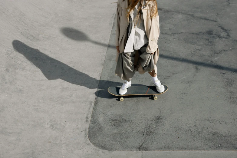 a young woman wearing a long trench coat riding on a skateboard