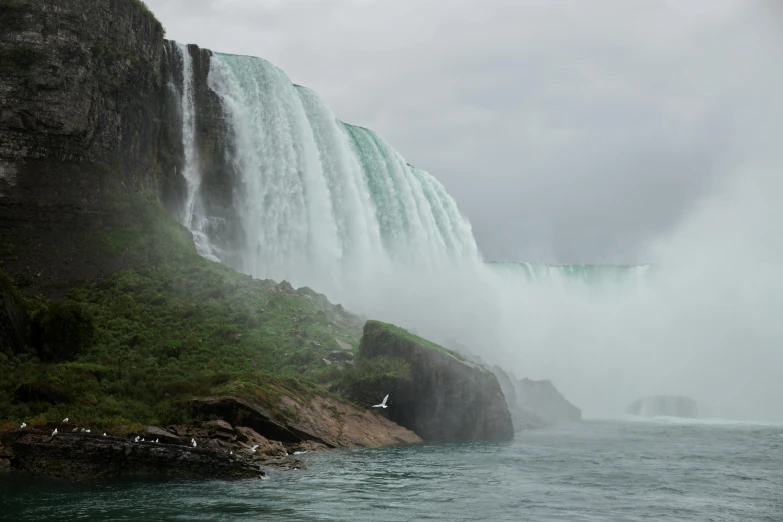 two people standing at the base of the falls