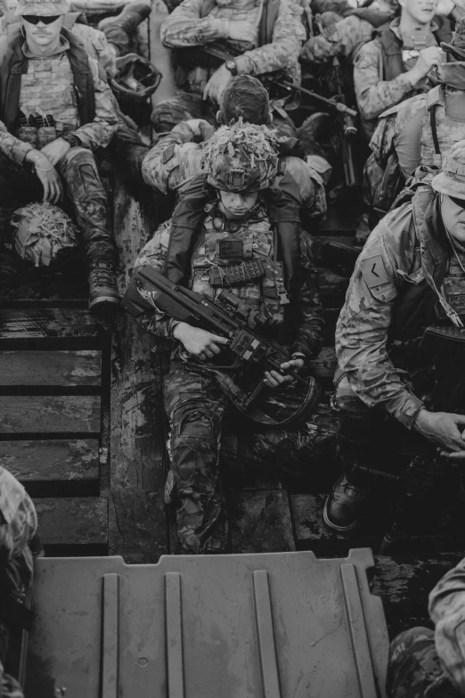 several military men in uniform and weapons, one in the background with other