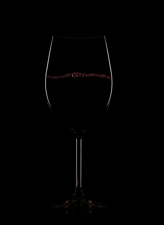 a wine glass with wine inside it on a black surface