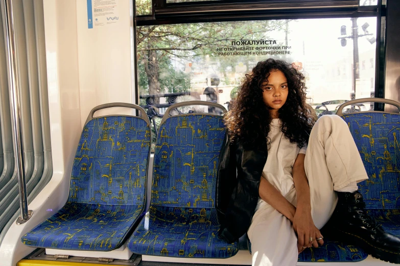 a woman sitting in a bus looking into the camera