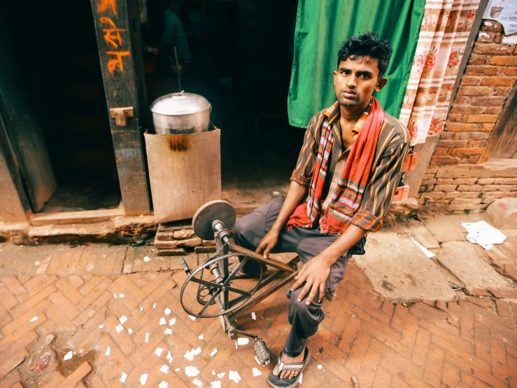 a man sitting on a broken bicycle on a brick sidewalk