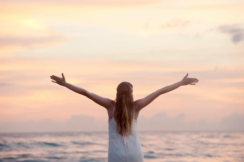 a woman with her arms outstretched over the ocean