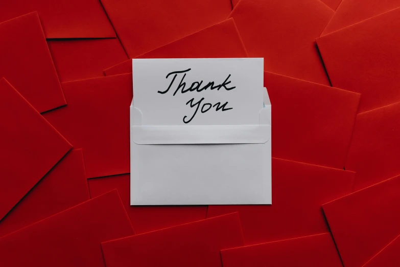 thank you note on paper against bright red paper