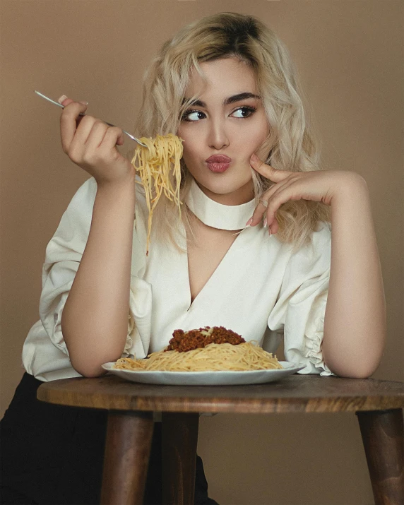 the woman is sitting at the table and eating spaghetti