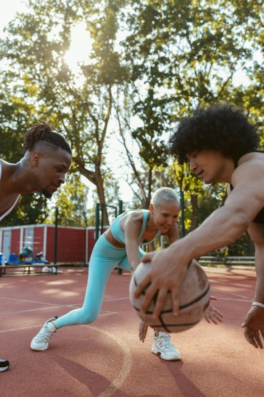 a woman is in position to reach for a basketball while another person crouches down in front of her