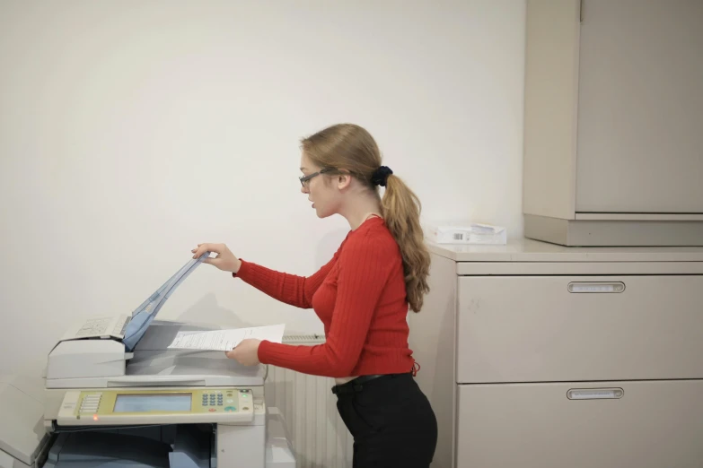 a girl with glasses is checking out the printer