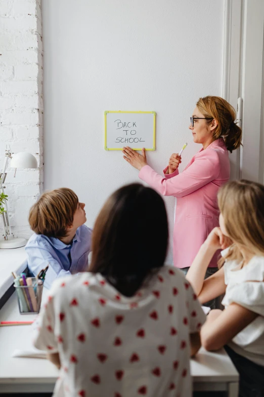 a woman with several children sitting around and looking at sticky notes on the white board