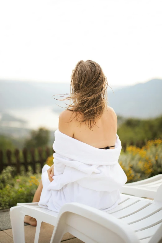 a young woman wrapped up and looking out over a flowery valley