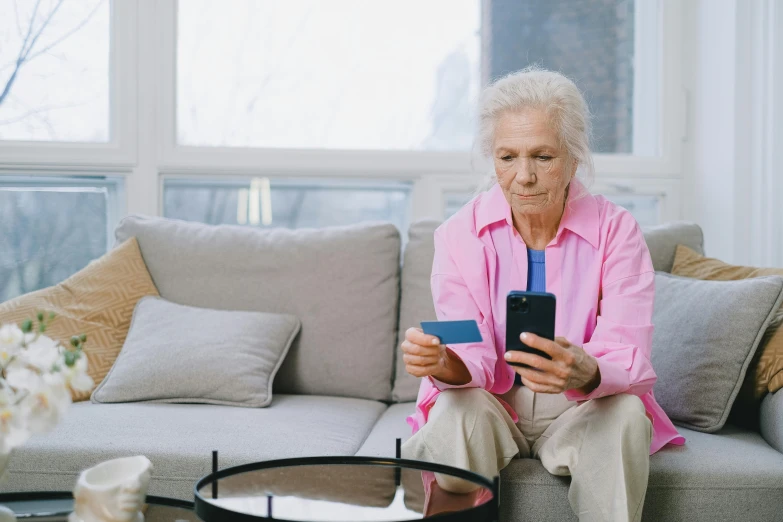 a woman is on her smartphone while she looks at a card