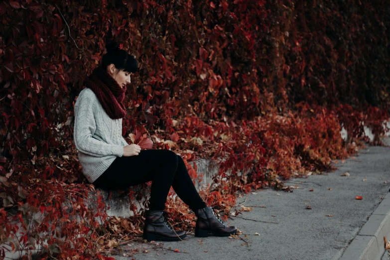 a woman is sitting against the wall in her scarf