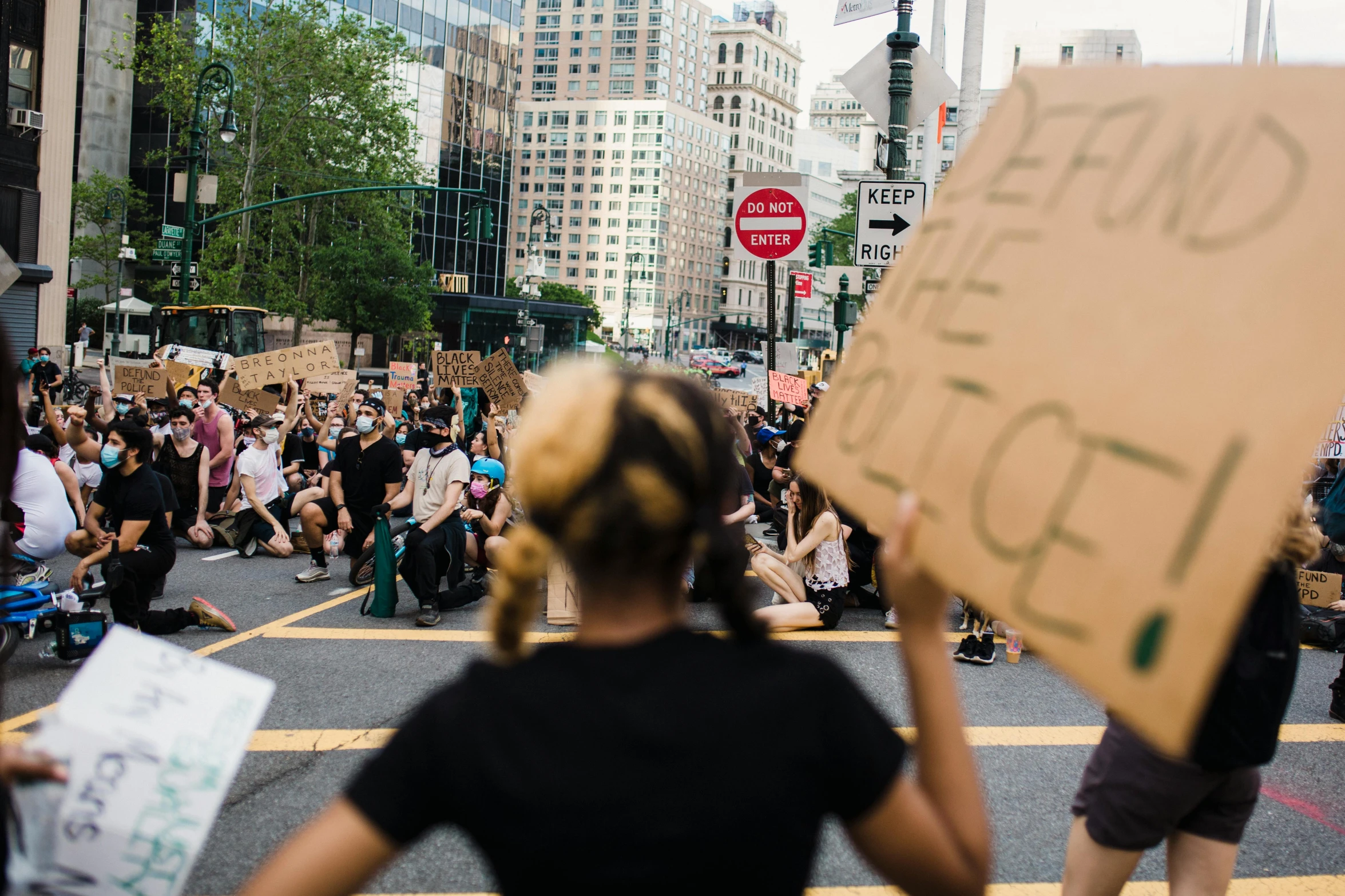 a woman holding a cardboard sign in front of the crowd