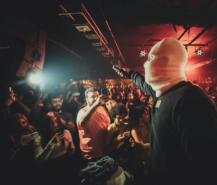 man holding cell phone in front of a crowd of people