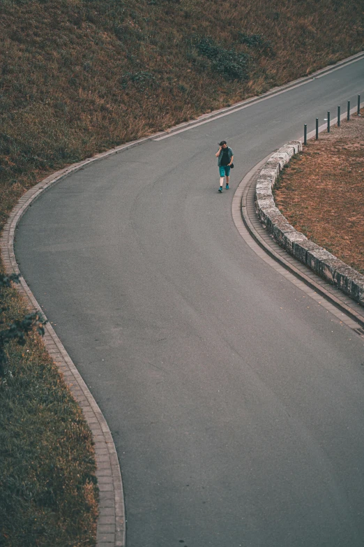 man in blue jacket skateboards down curved roadway