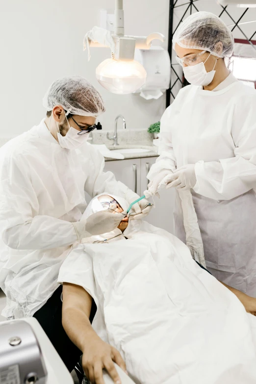 two doctors in white outfits work with the patient