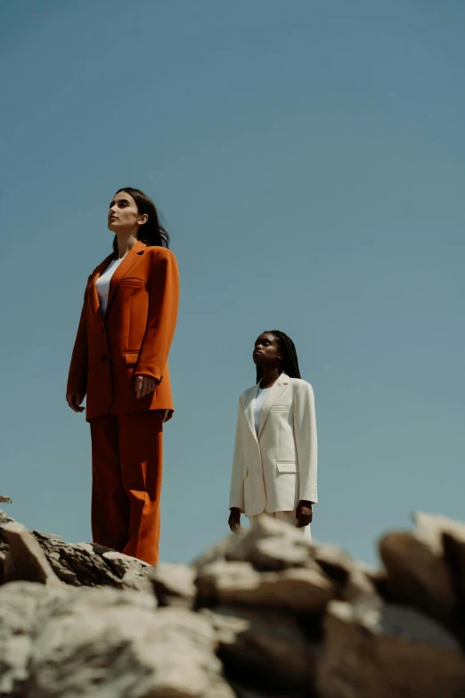 two woman standing next to each other on a rock