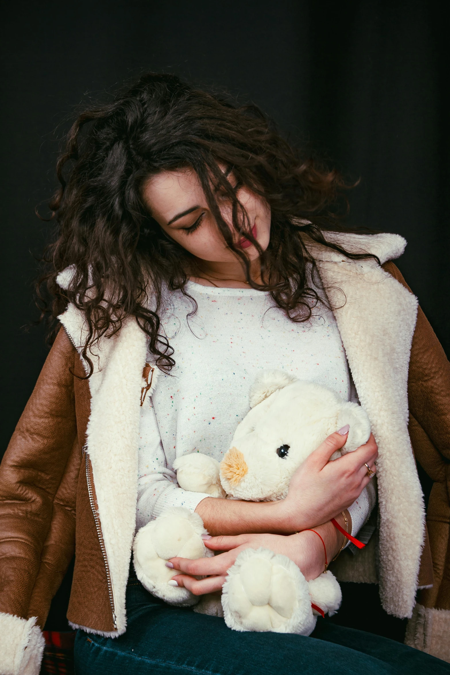 a young woman sitting in a chair with a stuffed animal