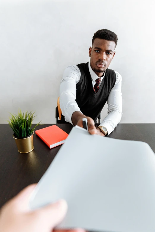 a black man is sitting at a table and showing someone soing