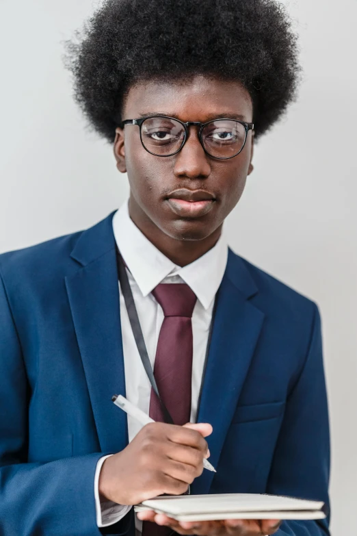 young man in a suit and glasses writing on a book