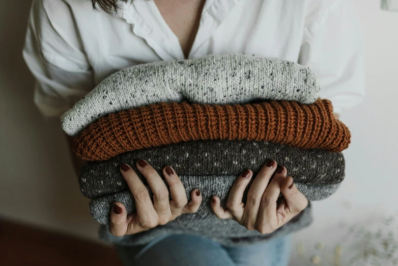 two hands holding a pile of knits