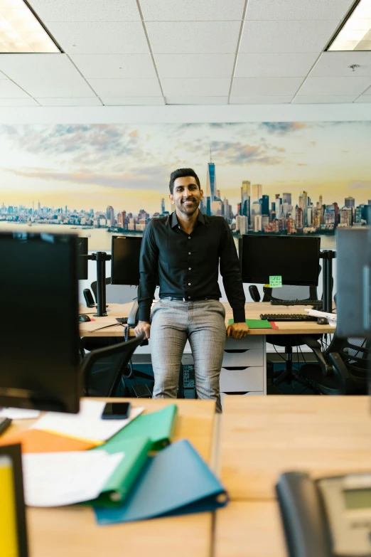 a man standing in an office with several desktop computers on the desk