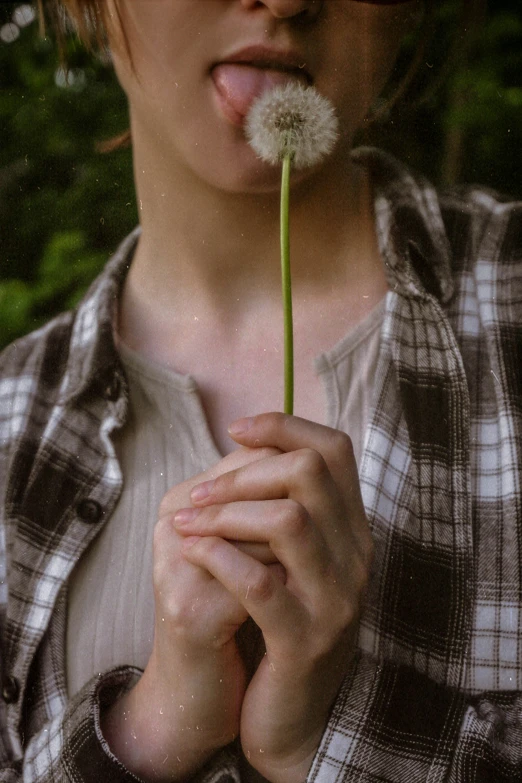 a woman holding a flower and blowing on it