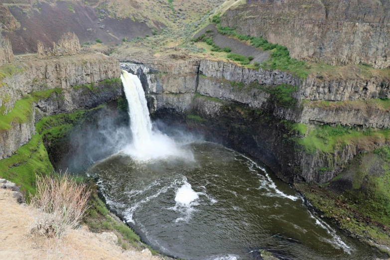 a large waterfall in a canyon with lush green foliage