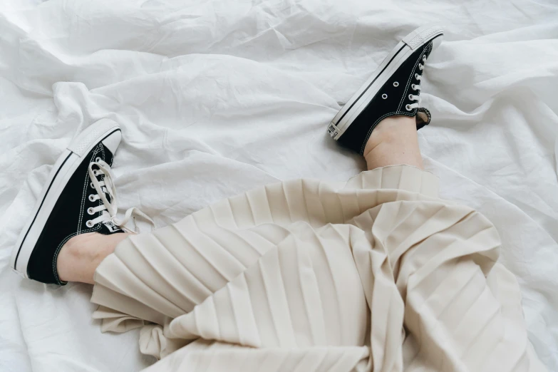a person laying in bed wearing black and white sneakers