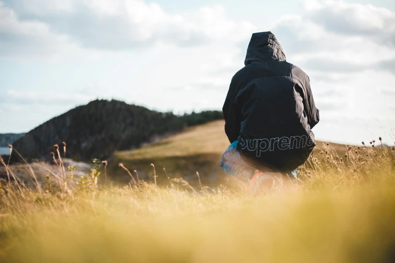 man sitting on top of hill with his skateboard