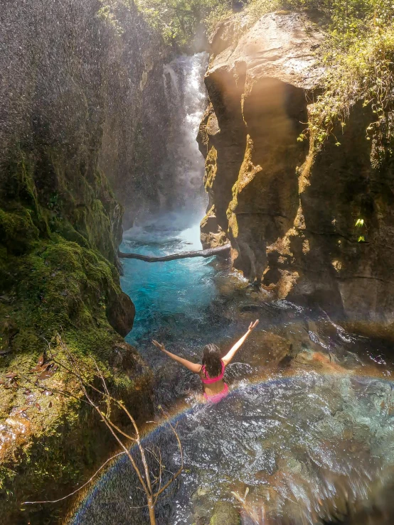 a woman hanging out in the pool at the base of a waterfall