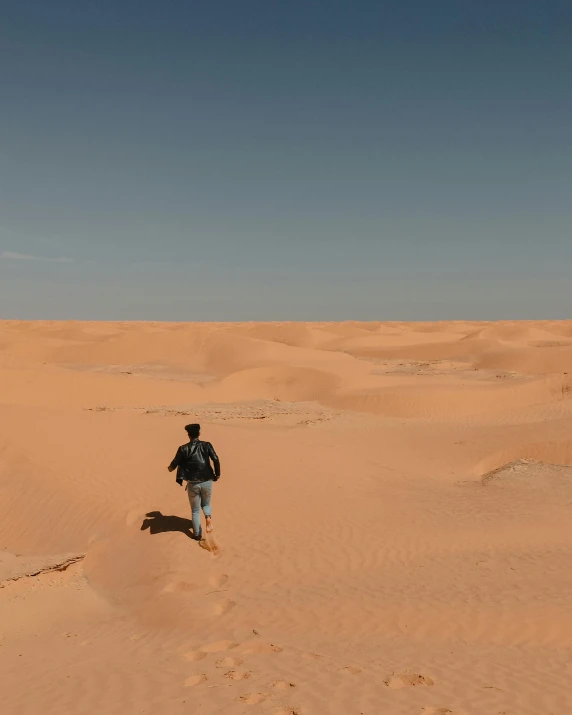 man walking in the middle of sand dunes