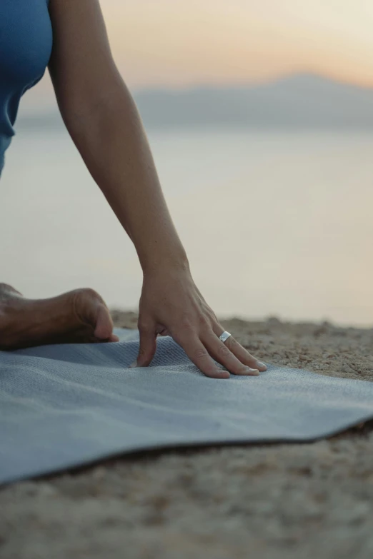 a woman stretches for the beach at sunset