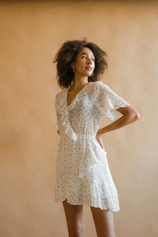 a young woman poses in her dress against a beige background