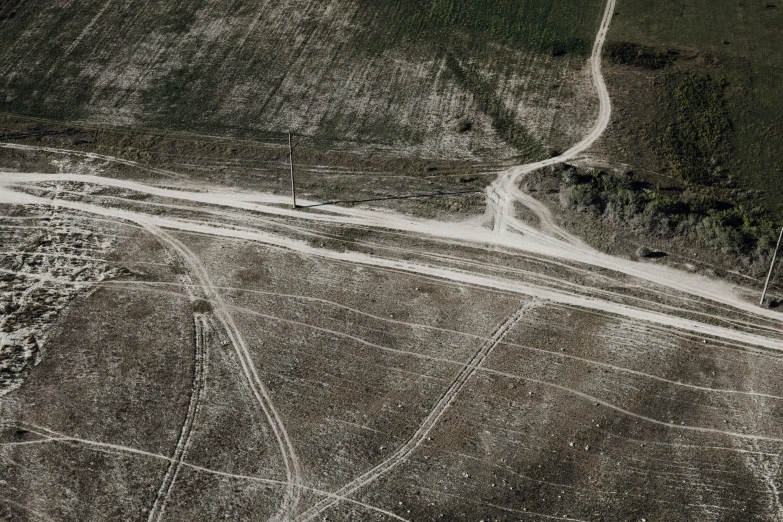 an aerial s of a dirt and grass covered area with two roads