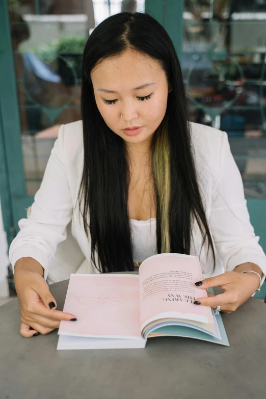 an asian girl reading a book with a serious expression