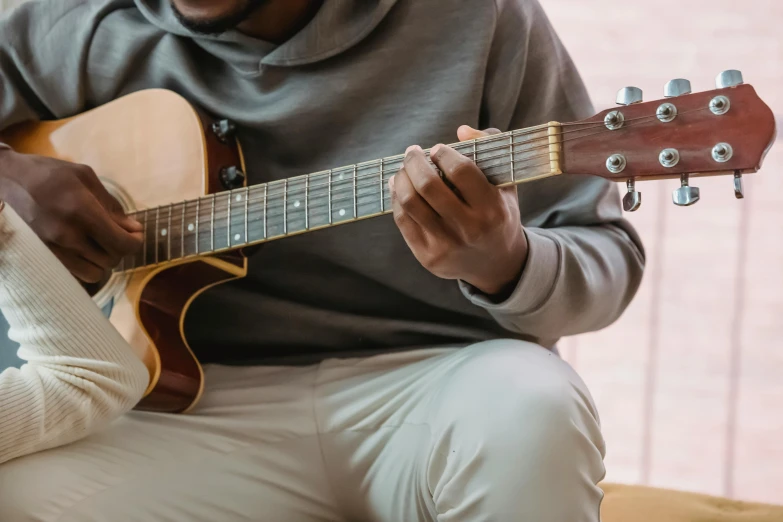 a man playing an acoustic guitar while another person looks on