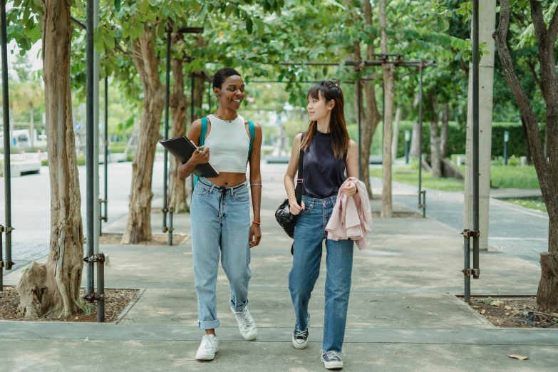 two girls walking down the street wearing casual jeans