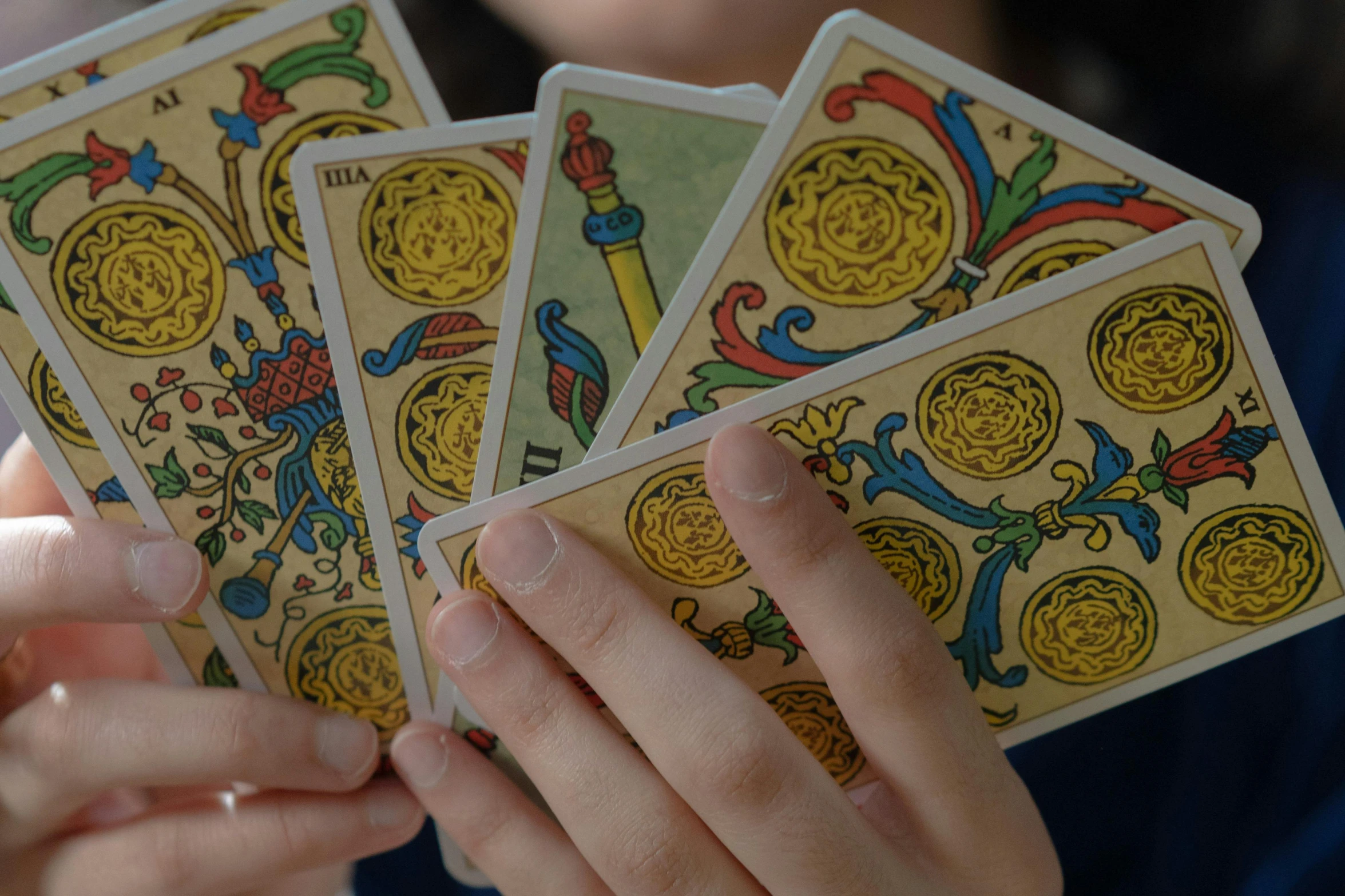 a woman holds four decked playing cards in her hand