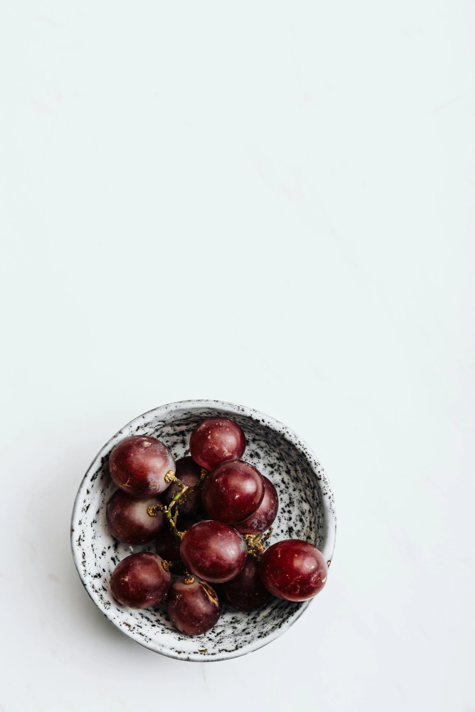 a bowl with red gs in it on a white surface