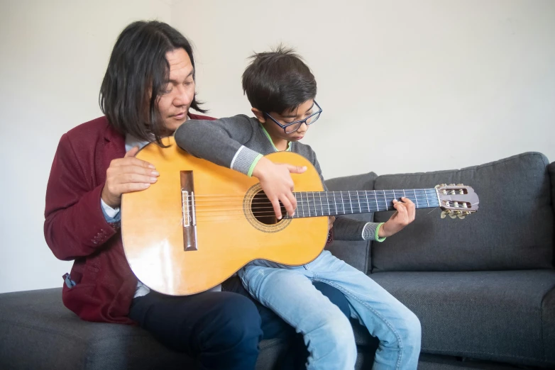 an adult playing a guitar with a child in front