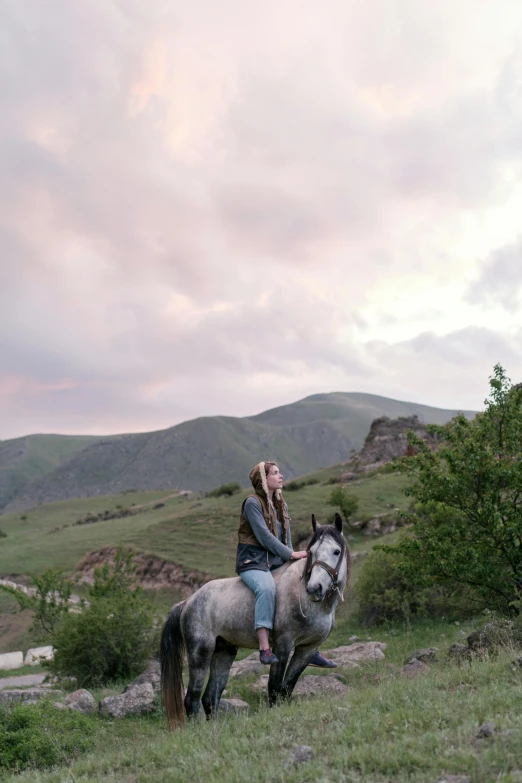 a woman riding a horse through a green field