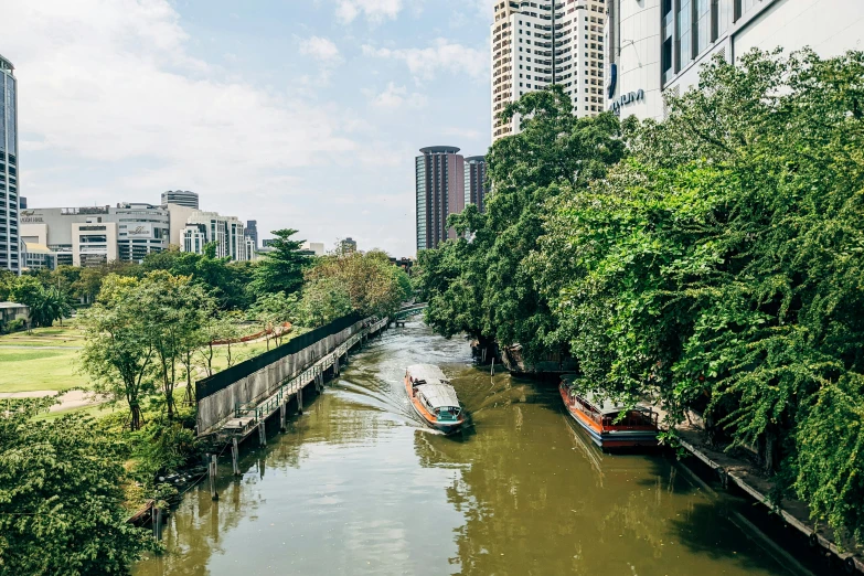 some boats are going down a river beside large buildings