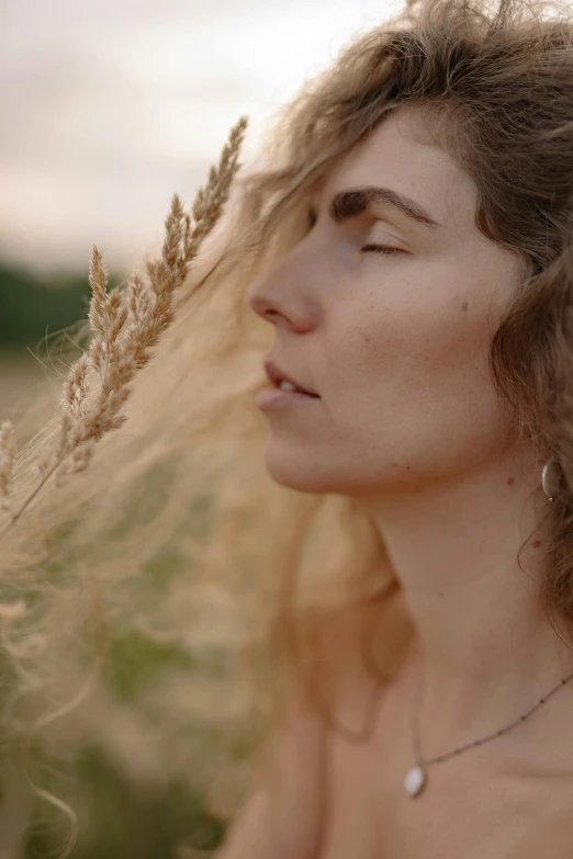 a young woman with long hair is standing in a field