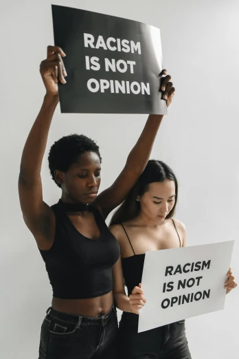 two girls holding signs with racism is not opinion