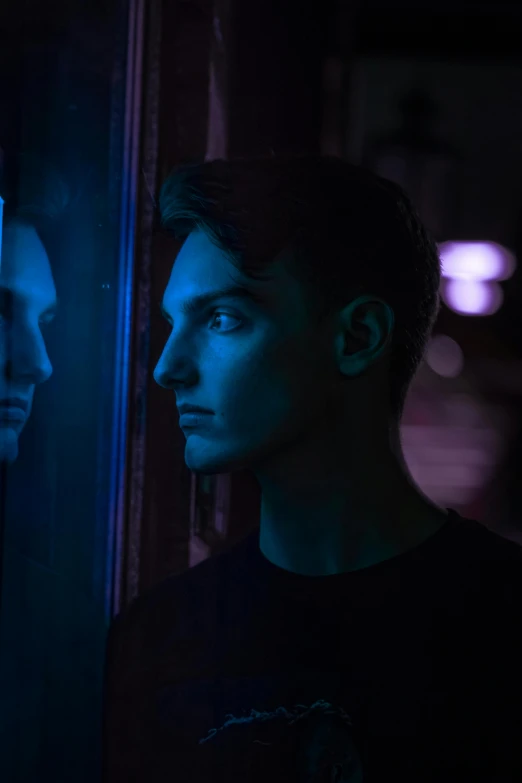 a male is standing next to the dark mirror