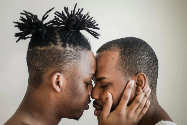 a pair of males face each other, while one is kissing