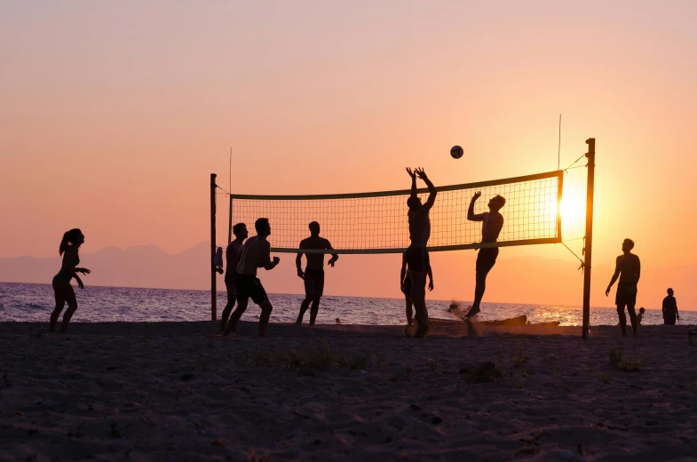 a group of people playing volley ball on the beach
